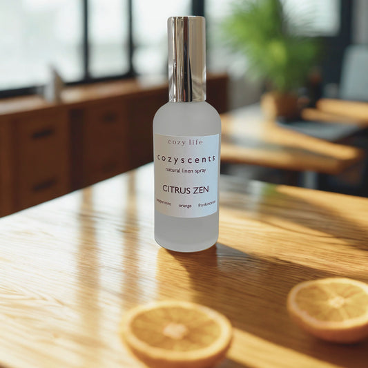 Cozy Life Cozyscents Citrus Zen room spray bottle on a wooden table with sliced oranges.