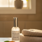CozyLife Citrus Zen Linen Spray bottle on a counter with towels and a plant in the background