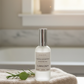 Bottle of CozyLife Clean Calm Linen Spray on folded towels with a blurred bathroom background
